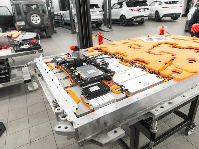 An electric vehicle traction battery pack opened on a workshop bench for module-level service