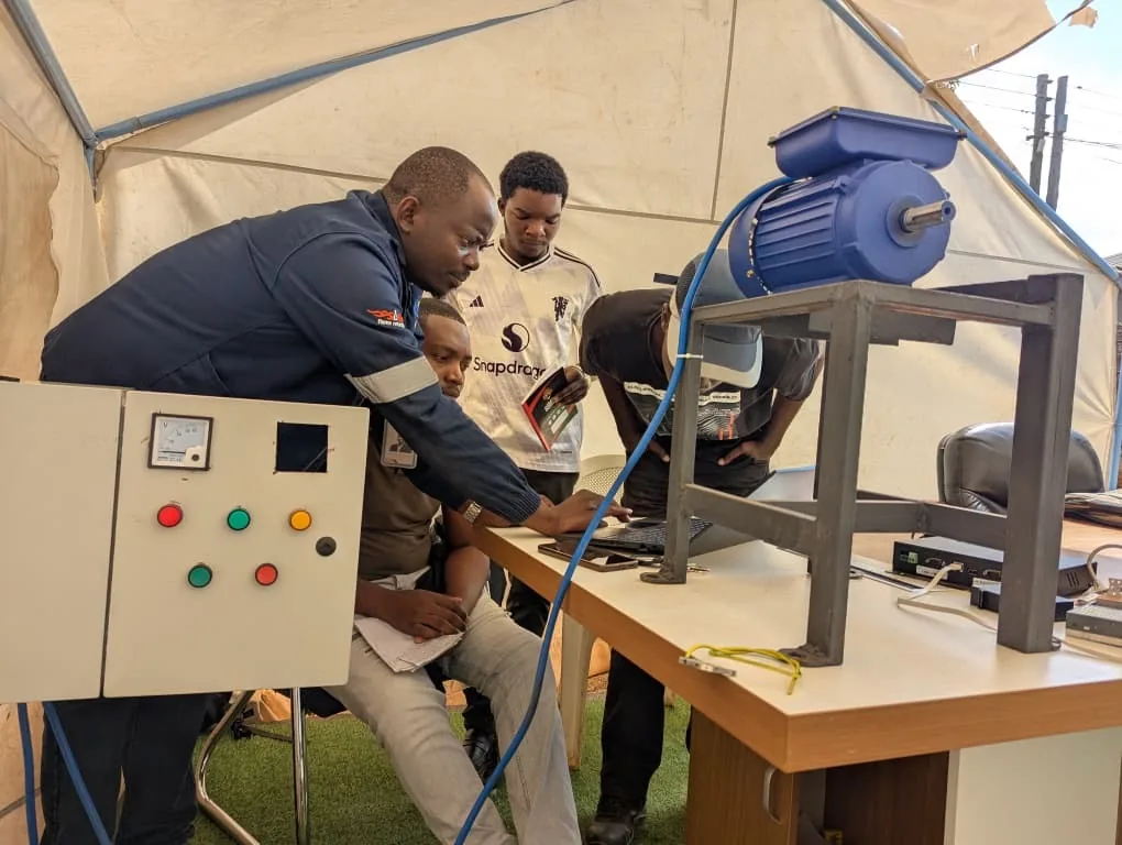 Trainees wiring a motor-control panel with an HCS instructor